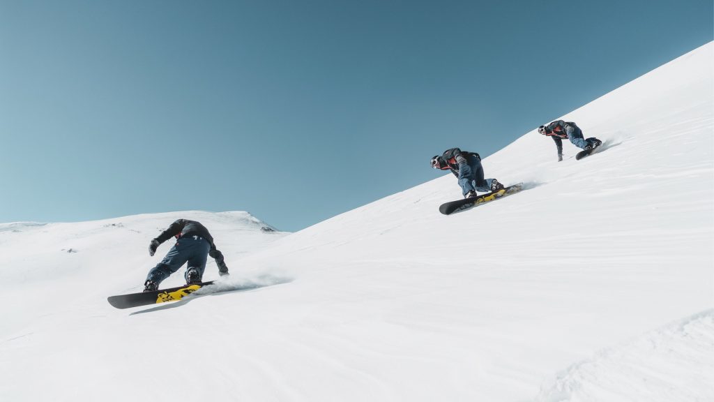 Skieurs sur une piste enneigée en station, sous un ciel bleu, lors de vacances au ski dans les Alpes