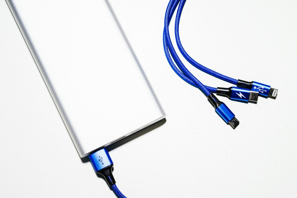 Batterie externe reliée à un smartphone par un câble USB, posée sur un sac de randonnée