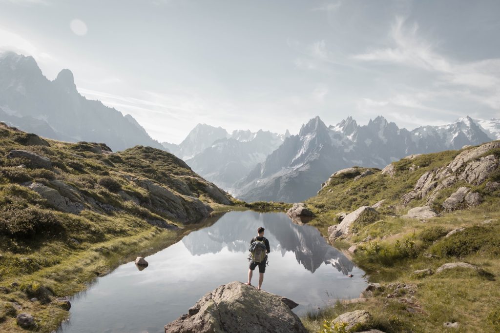 Lac de montagne entouré de sommets et de forêts de conifères sous un ciel d’été