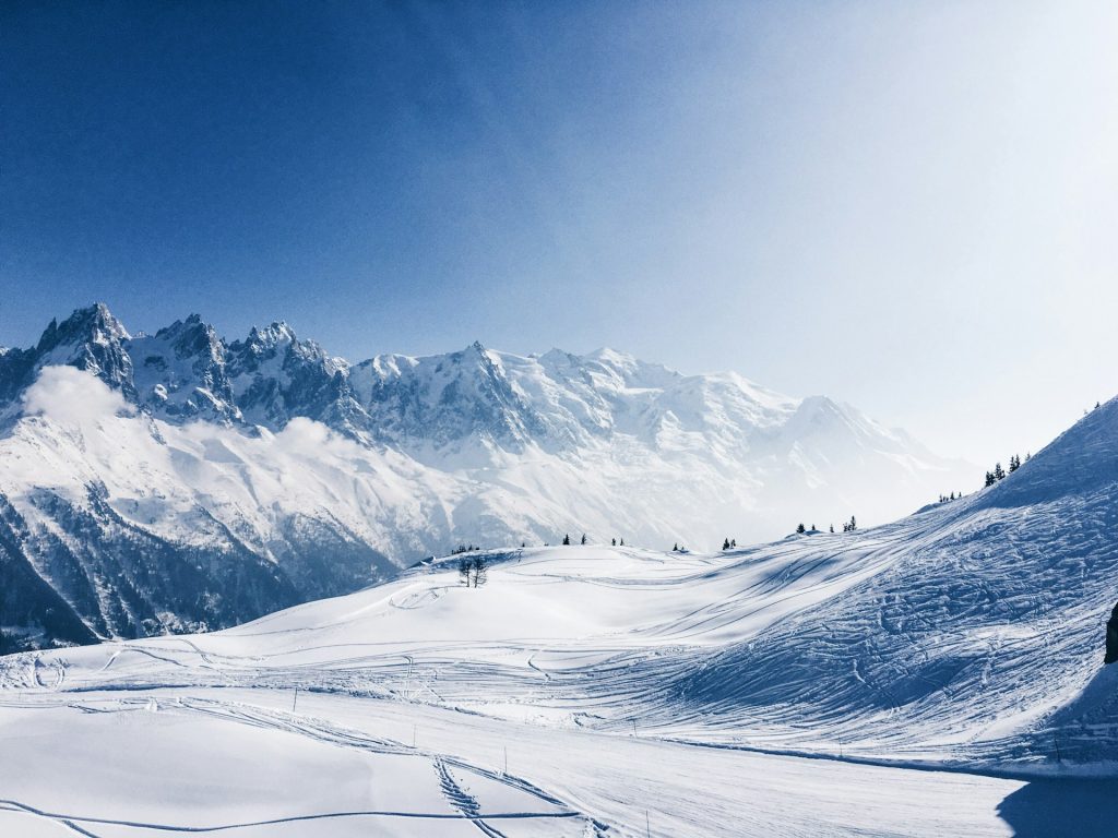 Paysage de montagne enneigé en hiver, sapins et sommets sous le soleil