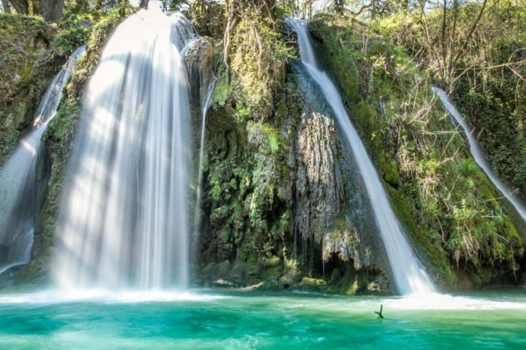 Cascade du Grand Baou coulant le long d’une falaise calcaire entourée de pins, dans le Luberon