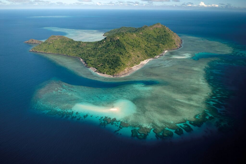 Plage de sable bordée de végétation tropicale au bord du lagon de Mayotte