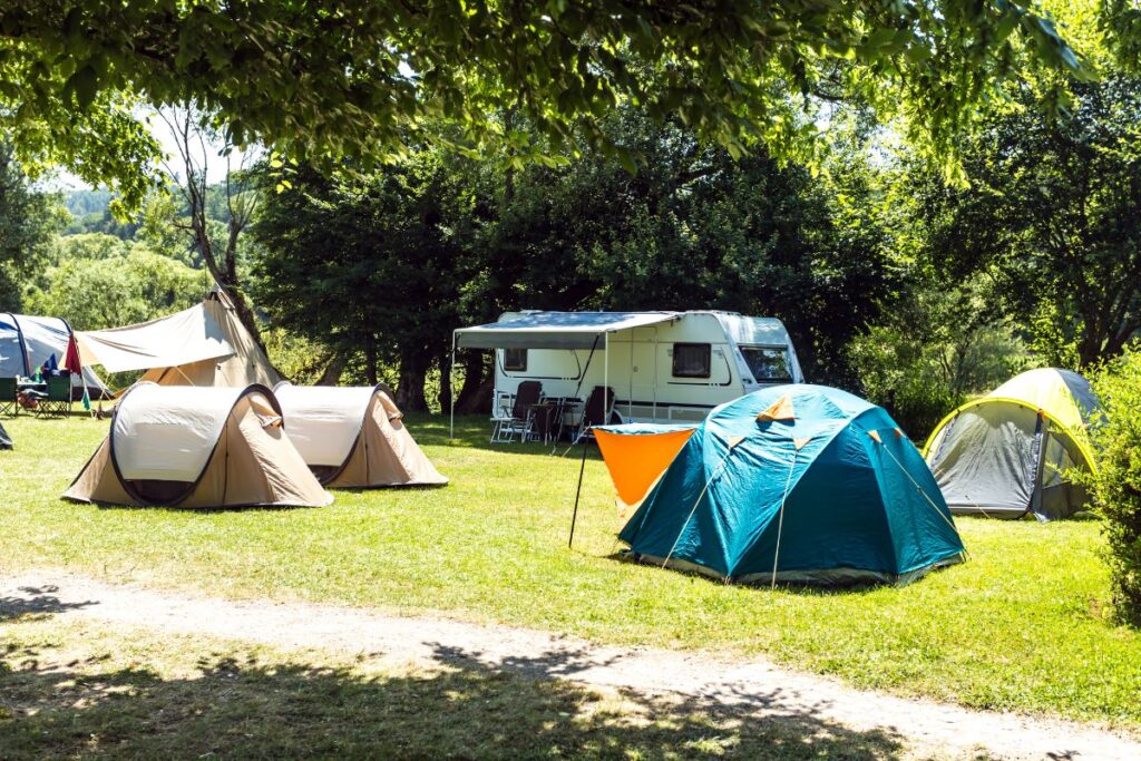 Tentes installées sur des emplacements herbeux ombragés dans un camping traditionnel en France