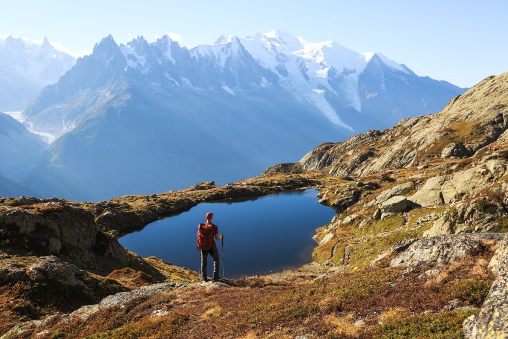 Randonneurs sur un sentier du Tour du Mont-Blanc face aux sommets enneigés