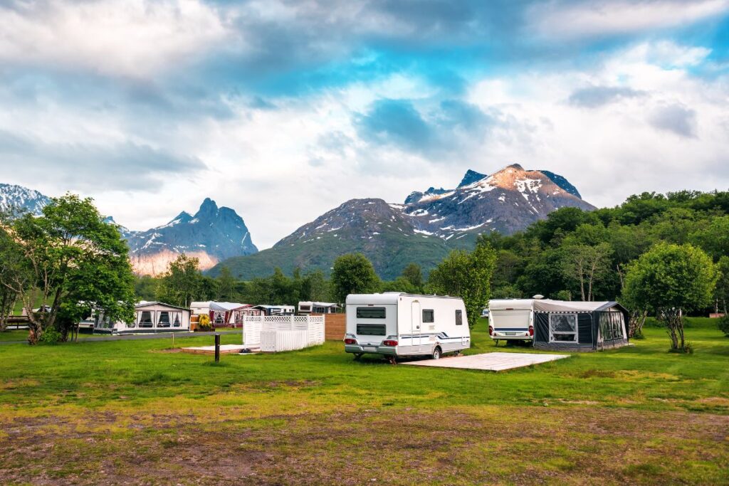 Tentes installées dans un camping de montagne face aux sommets des Alpes en été