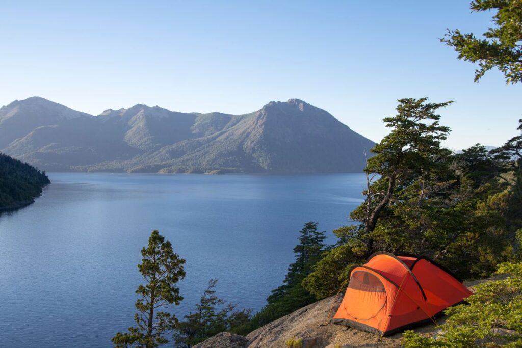 Emplacement de camping en montagne avec tente et vue sur les sommets de l’Oisans
