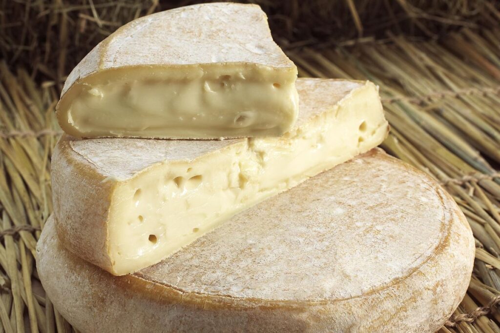 Reblochon fermier de Haute-Savoie entier et coupé sur une planche en bois