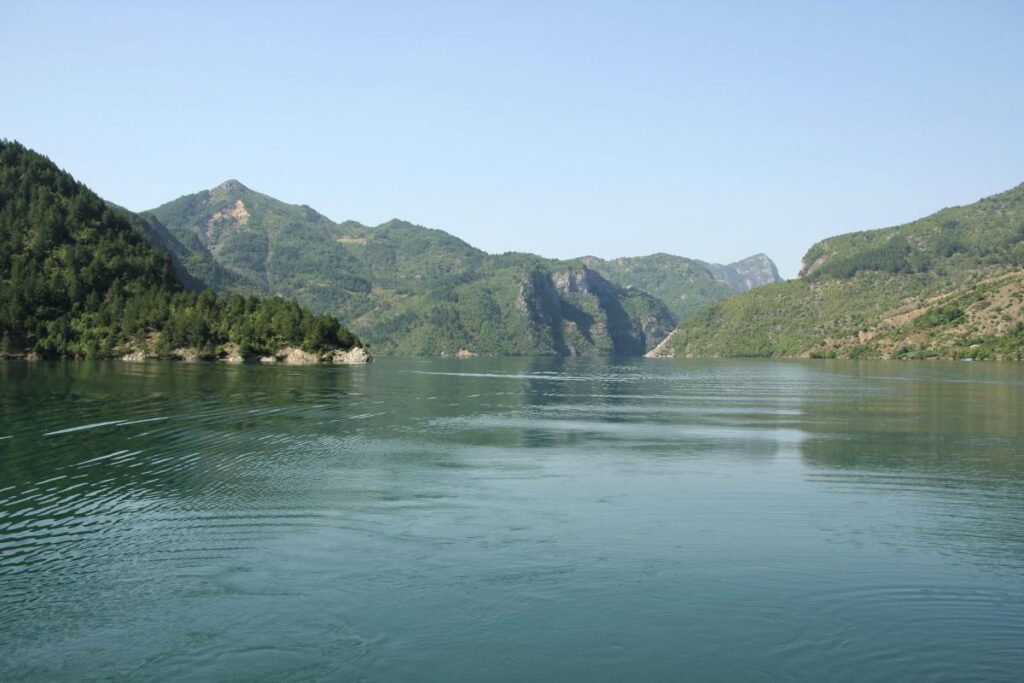 Lac de Komani serpentant entre des falaises boisées dans le nord de l’Albanie