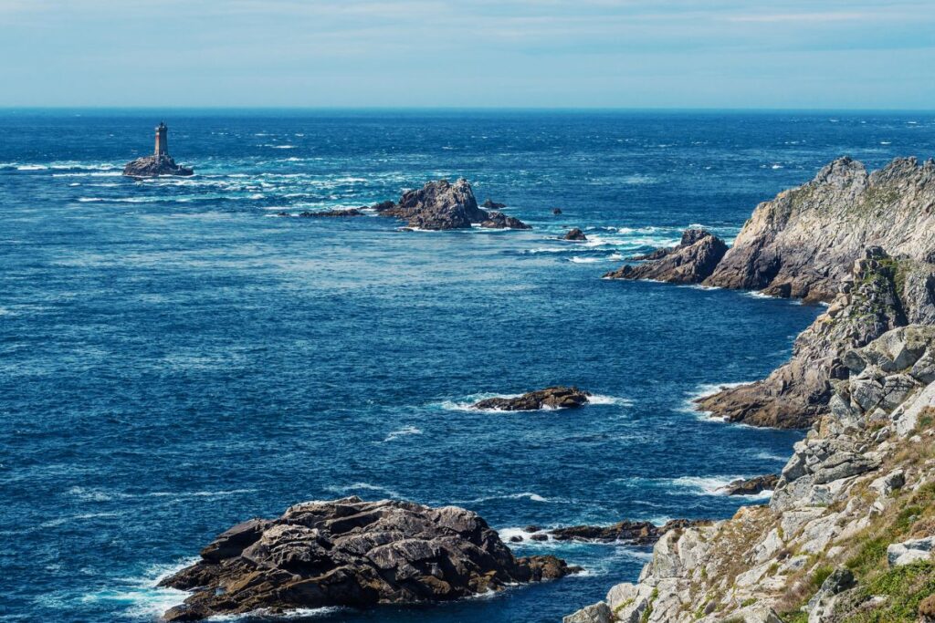 Falaises granitiques de la pointe du Raz battues par l’océan, avec le phare de la Vieille, dans le Finistère