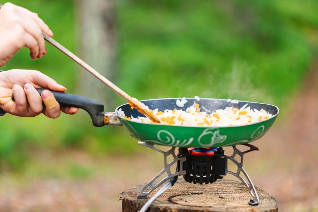 Réchaud à gaz de camping et casserole posés au sol lors d’un bivouac
