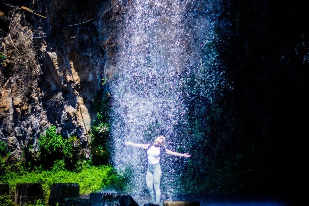 Voiture passant sous le rideau d’eau de la cascade des Anges sur la côte sud de Madère
