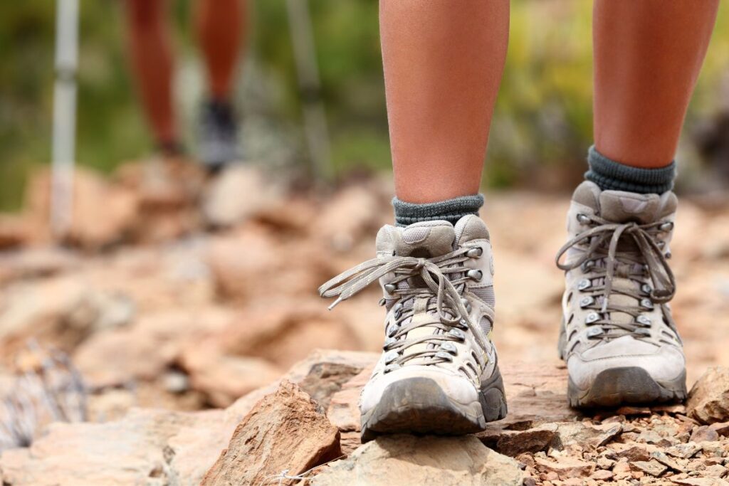 Alpiniste en chaussures de haute montagne sur un sentier rocheux au-dessus des glaciers