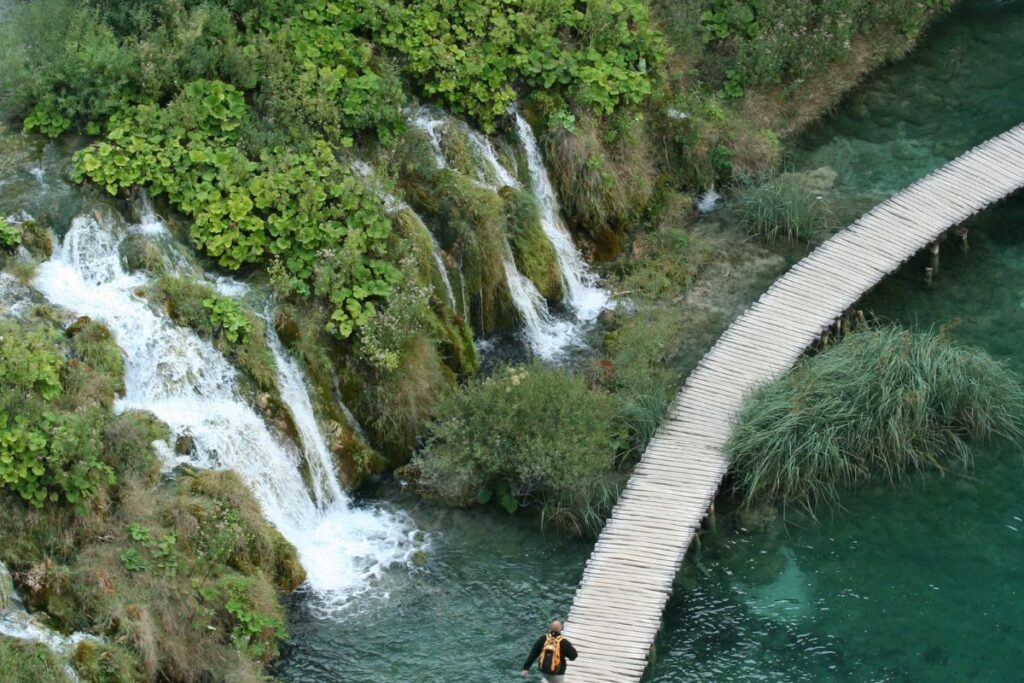 Sentier de randonnée longeant un lac turquoise dans la forêt de Plitvice