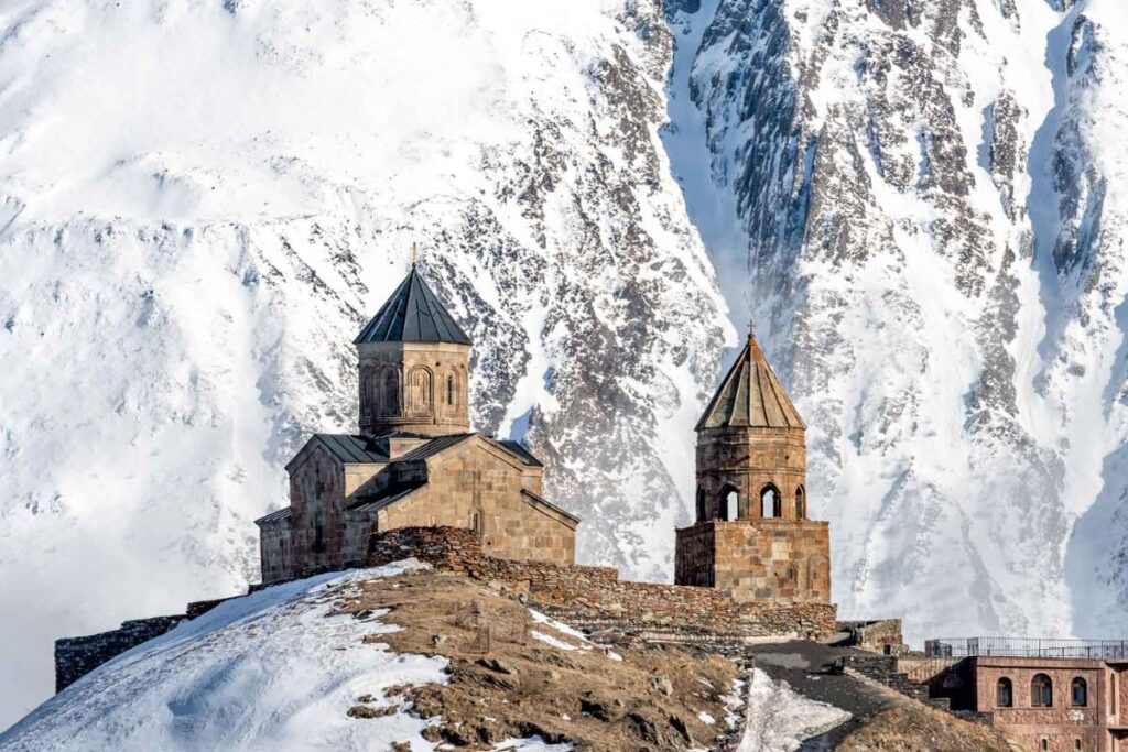 Église de la Trinité de Gergeti sur sa crête herbeuse, face aux sommets enneigés du Caucase en Géorgie
