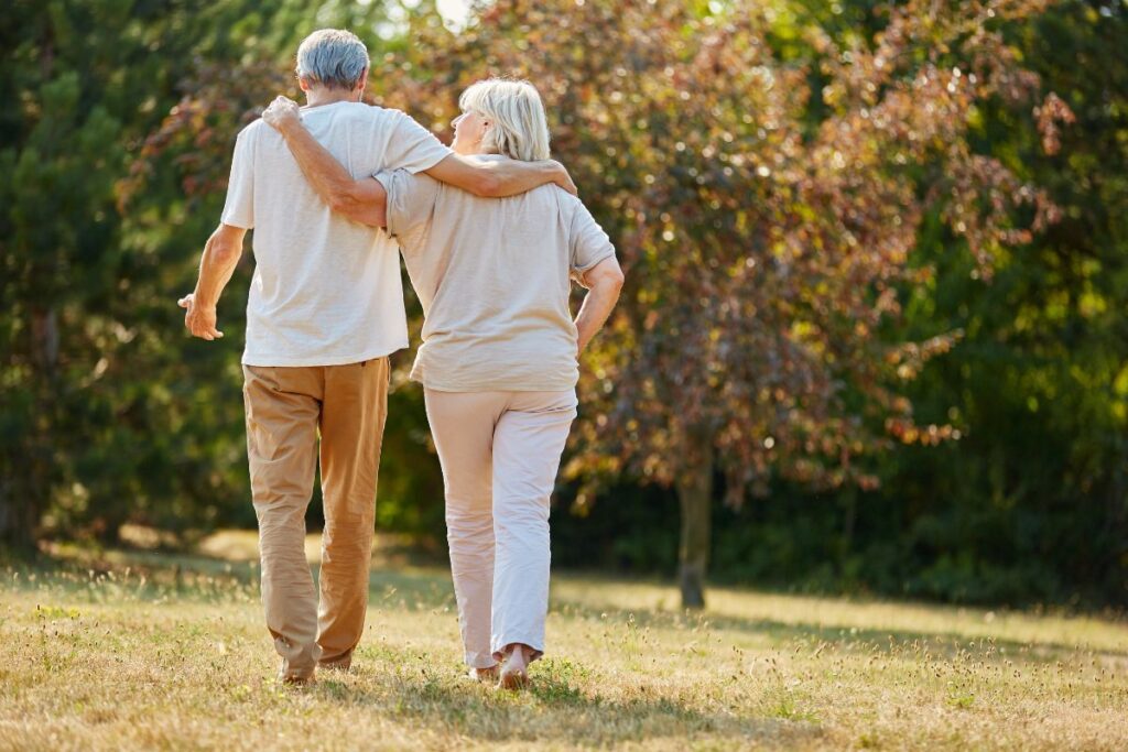 Randonneuse senior en montée sur un sentier de montagne, bâtons en main