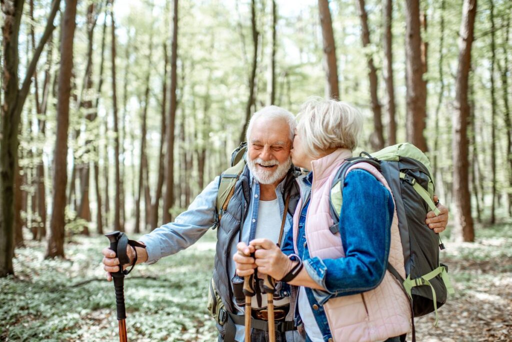 Randonneur âgé descendant prudemment un sentier caillouteux avec ses bâtons