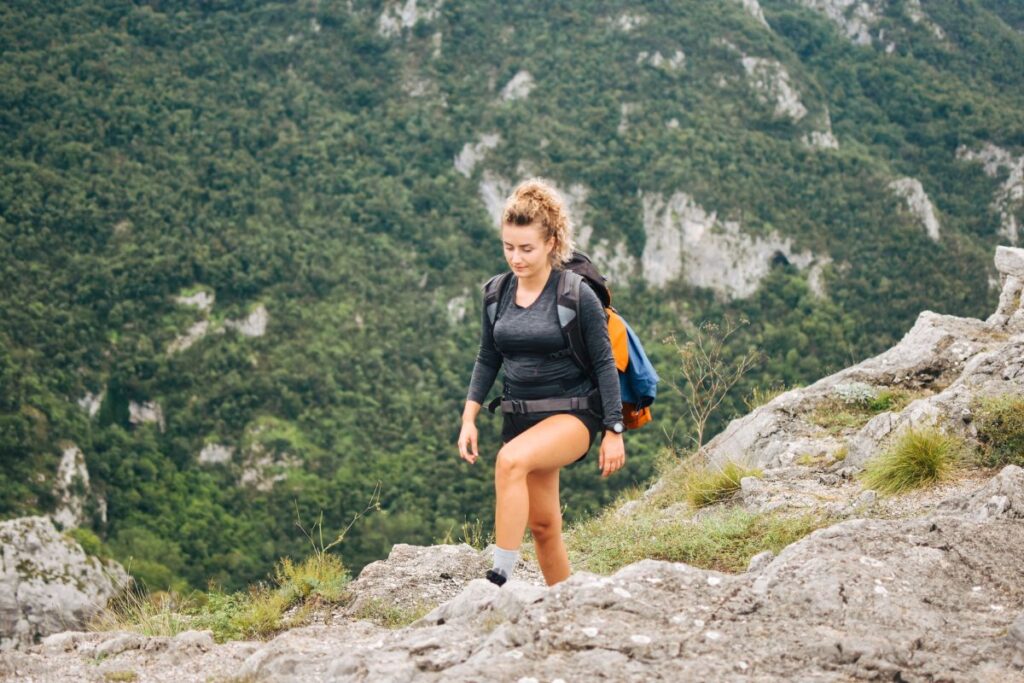 Randonneuse gravissant un sentier de montagne, jambes et fessiers sollicités par la pente