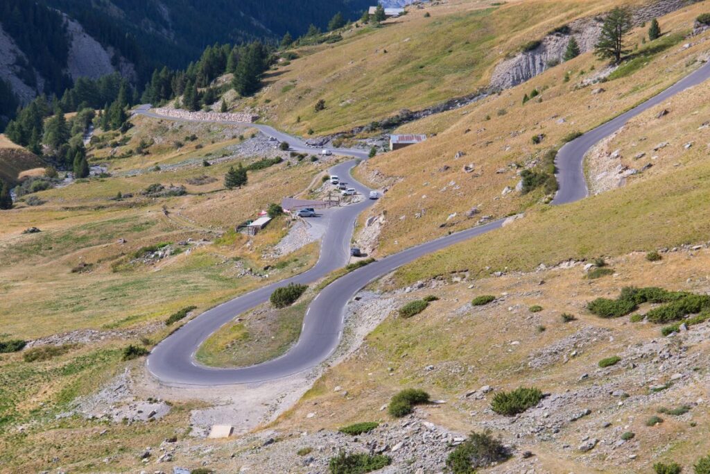 Route en lacets montant au col de Vars entre prairies d’altitude et sommets des Alpes du Sud