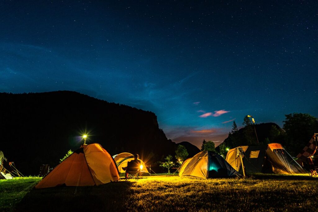 Tentes de camping éclairées de l’intérieur la nuit lors d’un bivouac