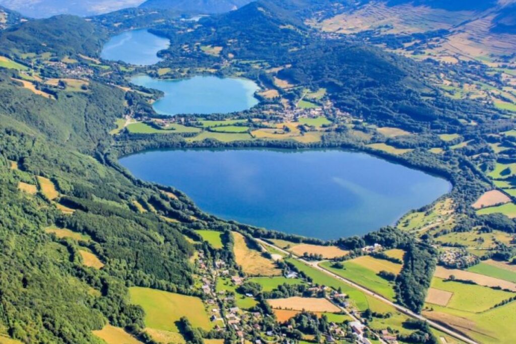 Rive boisée du grand lac de Laffrey sur le plateau matheysin, avec les montagnes de l’Isère en arrière-plan
