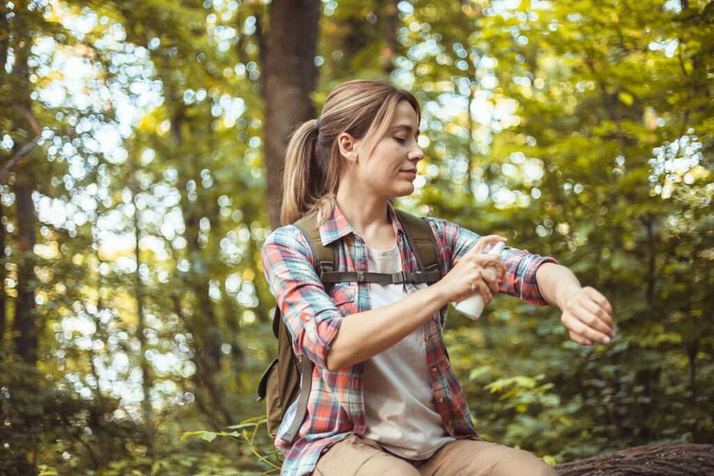 Randonneuse étalant une crème répulsive sur sa nuque avant une marche en forêt