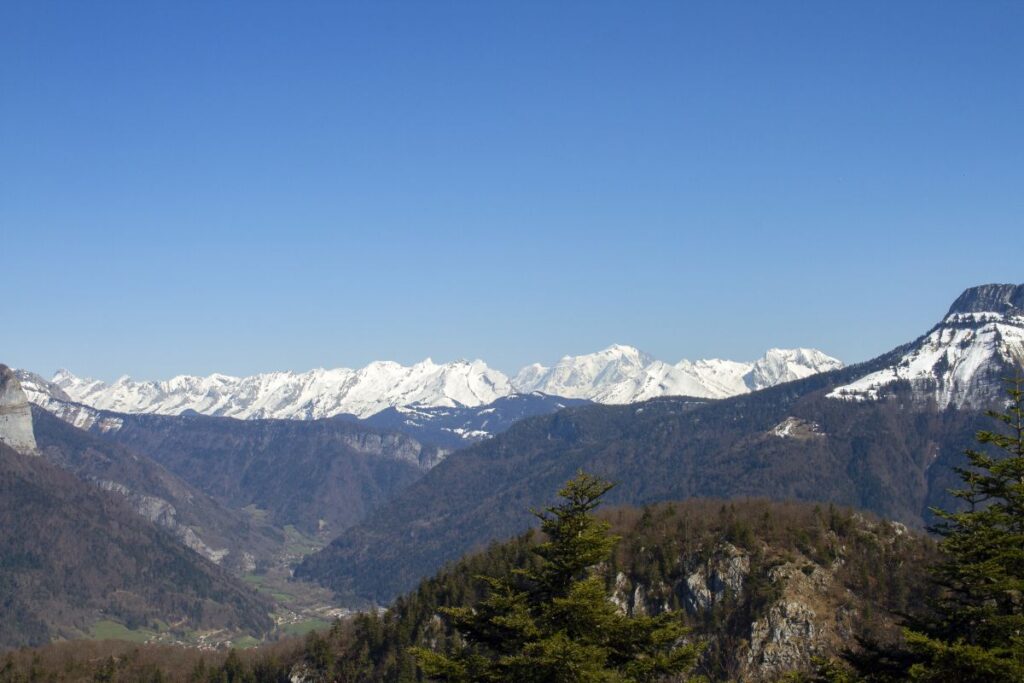 Alpages verdoyants de Champ Laitier près du plateau des Glières, avec chalets d’alpage et sommets du massif des Bornes