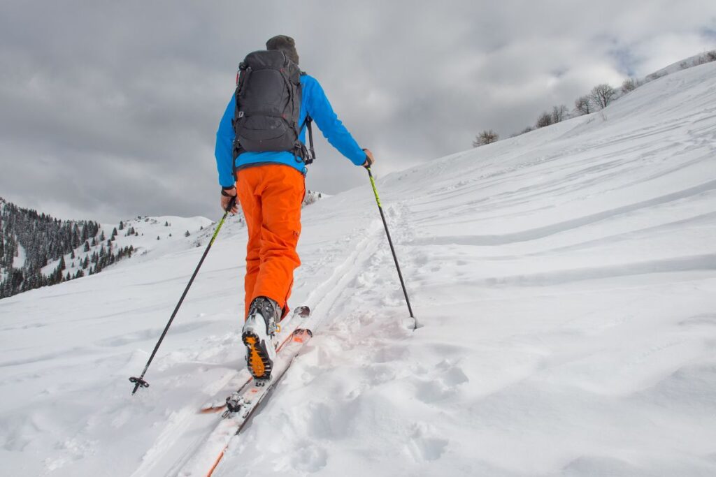 Groupe de skieurs de randonnée progressant en file sur un vallon enneigé en haute montagne