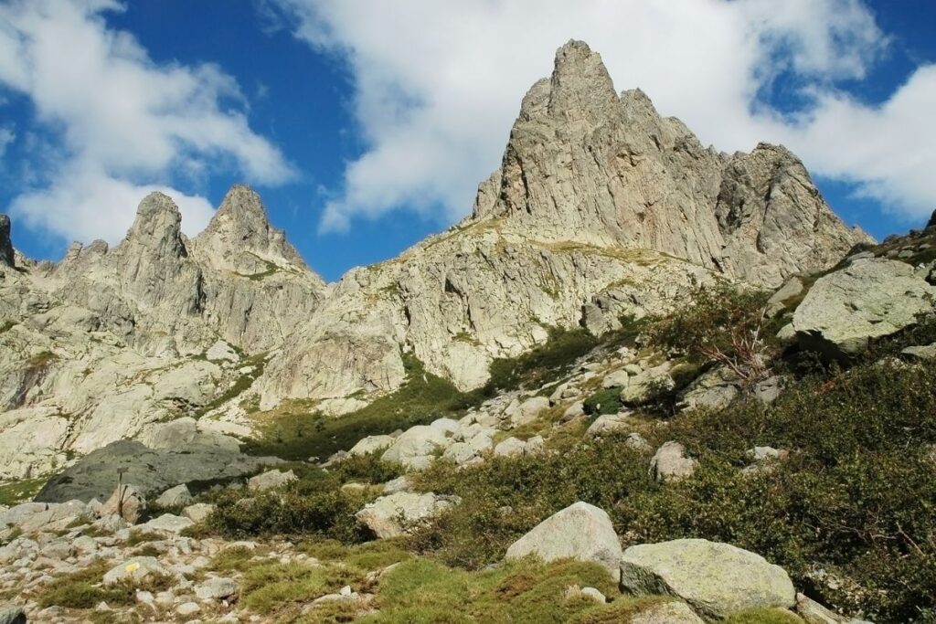 Randonneur au sommet d’un col du GR20 avec vue sur les montagnes corses