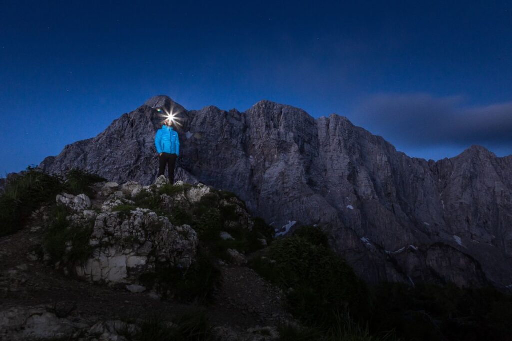 Chaussures de randonnée montantes éclairées par une lampe frontale sur un sentier rocailleux