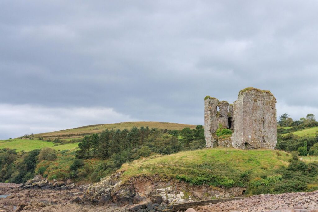 Sentier de randonnée entre collines vertes et murets de pierre sous un ciel nuageux en Irlande
