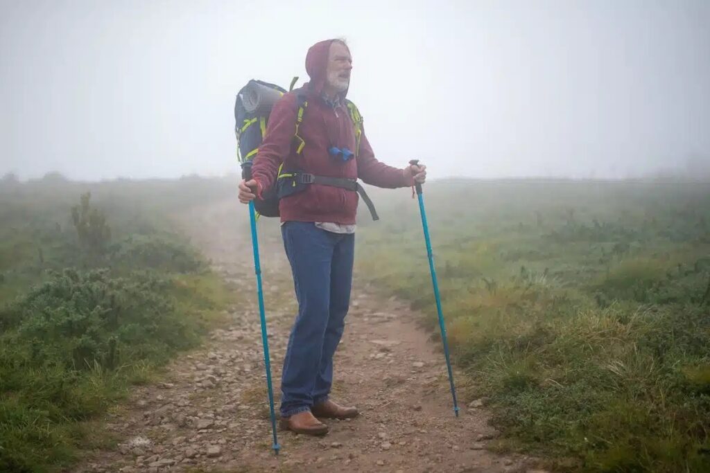 Randonneuse ajustant sa veste coupe-vent et sa couche chaude lors d’une pause en altitude