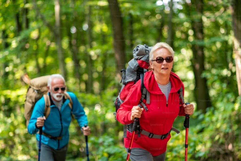 Randonneur senior marchant sur un chemin de campagne avec un sac à dos lesté pour pratiquer le rucking
