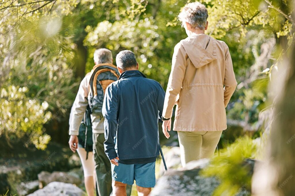 Couple de retraités marchant avec des sacs à dos sur une voie verte en forêt